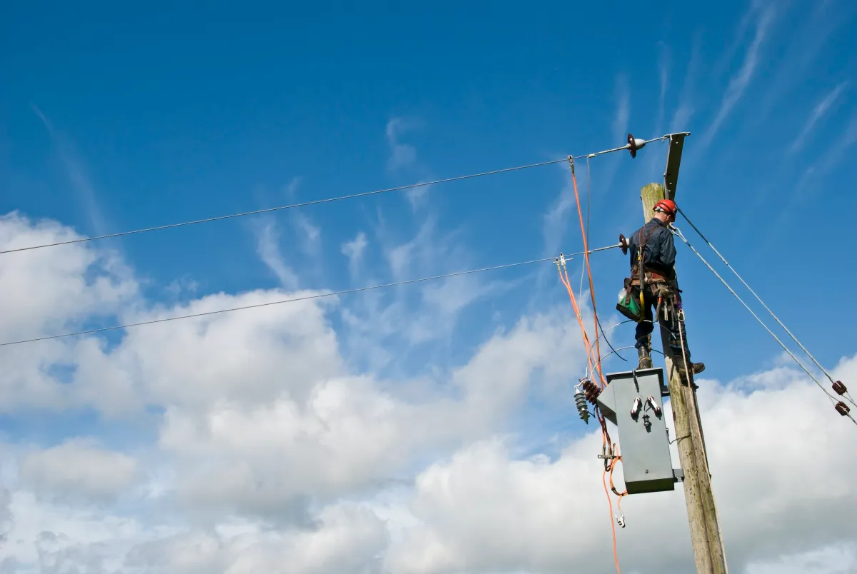 Lineman working on power pole — TechCrunch article on Amperesand seed round